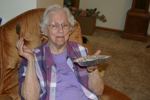 Grandma Assink, always the character, enjoying pie in her new apartment.